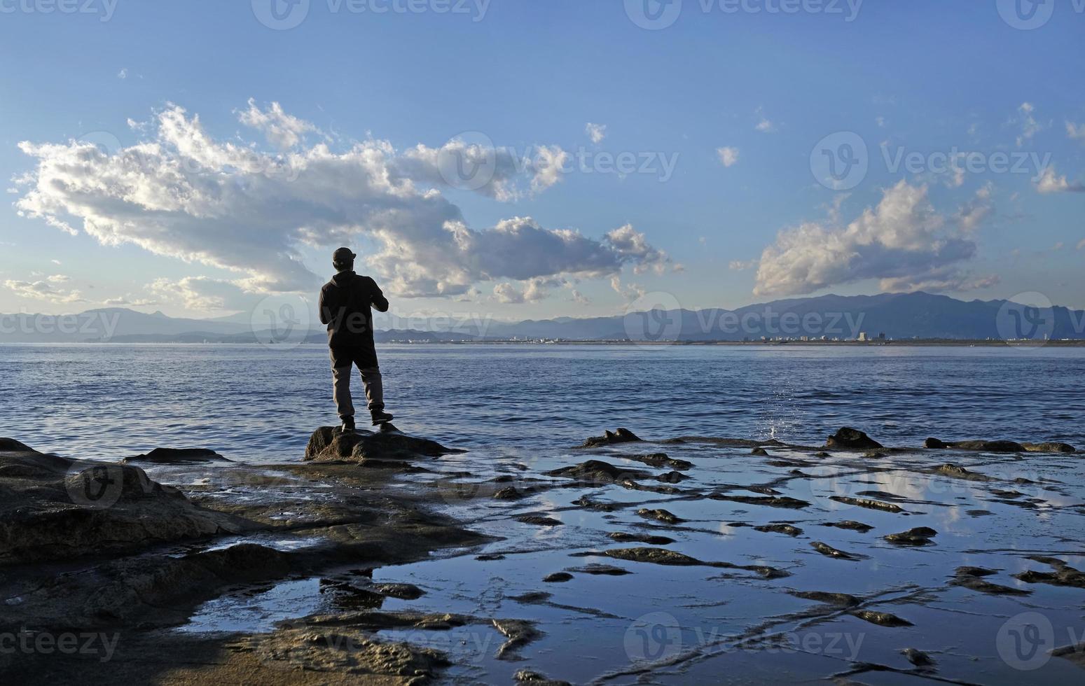 spettacolare scenario a il costa di enoshima, Giappone, con un' solitario pescatore in piedi a il bordo per il acqua foto