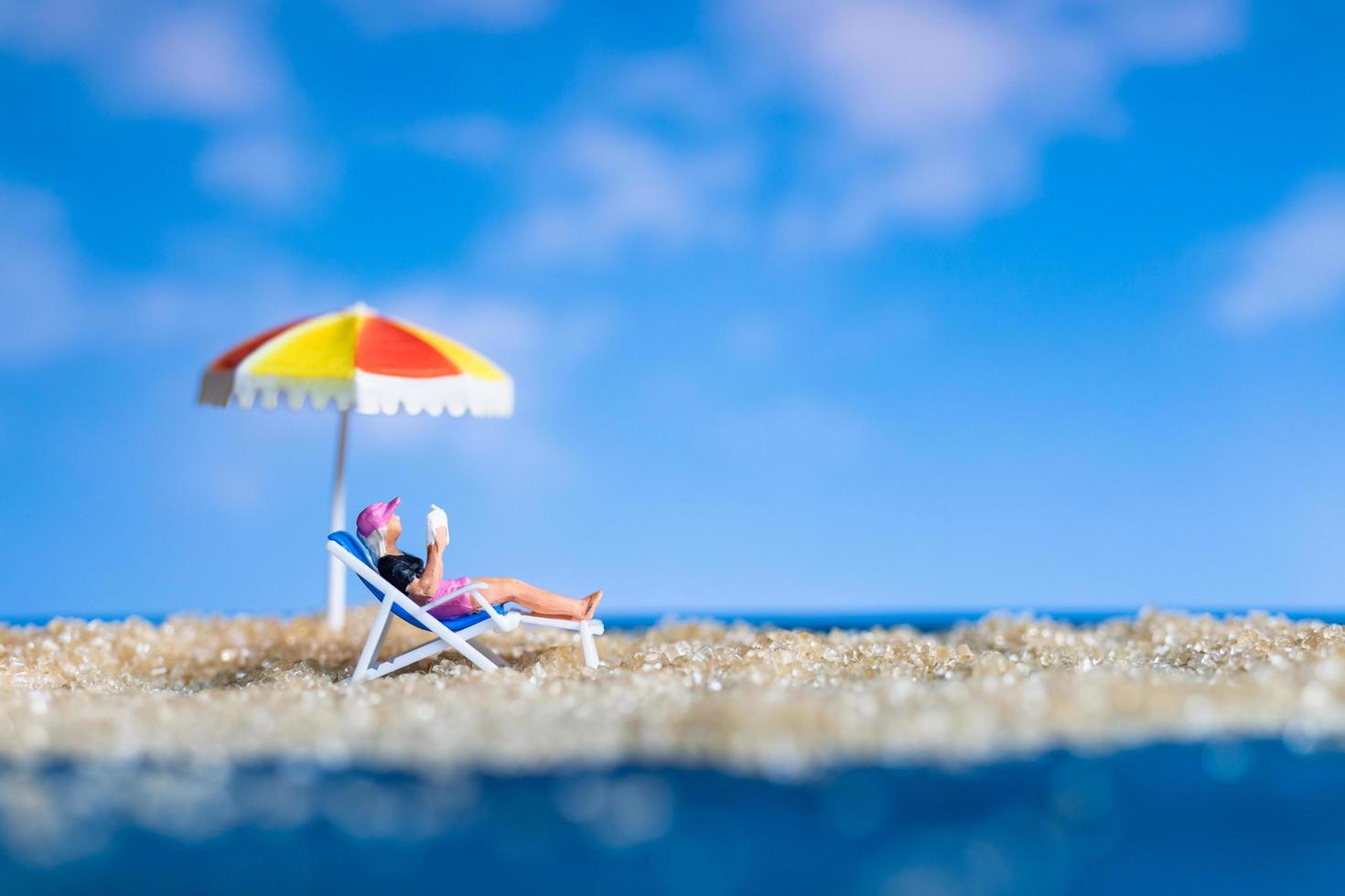 persona in miniatura che prende il sole sulla spiaggia foto