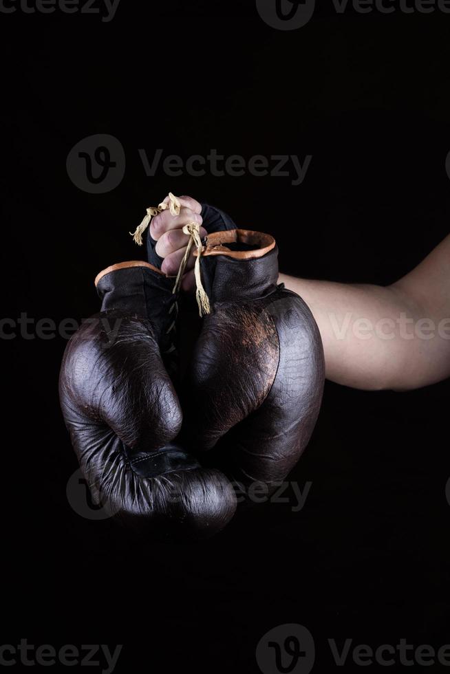 dell'uomo mano detiene un' paio di vecchio pelle Marrone boxe guanti foto