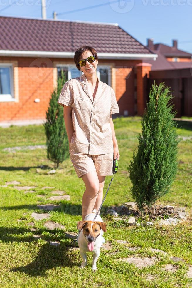 giovane donna indossare pigiama con sua cane su Giardino dietro la casa. il concetto di animali e amicizia o animale domestico proprietario e amore foto