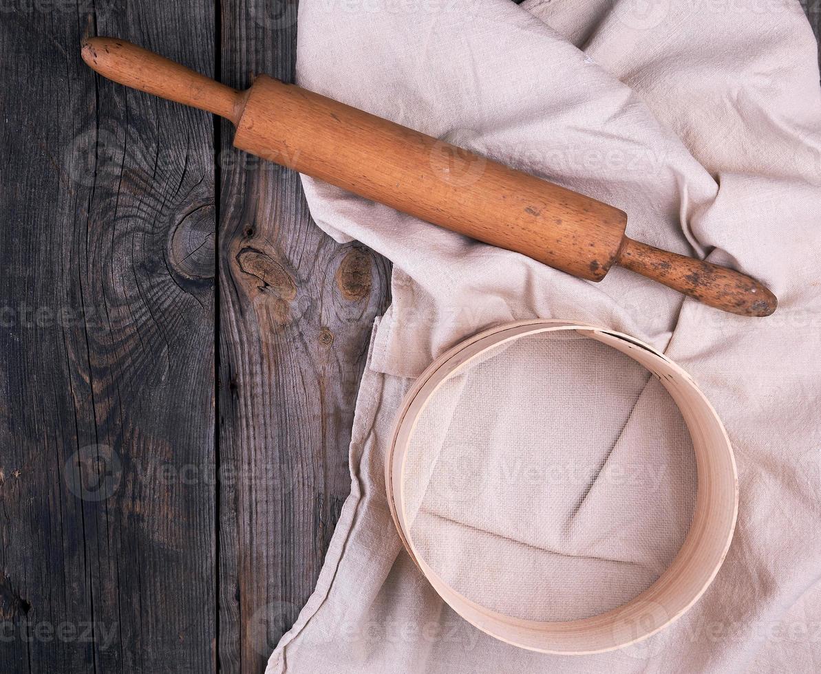 di legno rotolamento perno su un' tessile tovagliolo con ricamo e un' il giro setaccio foto