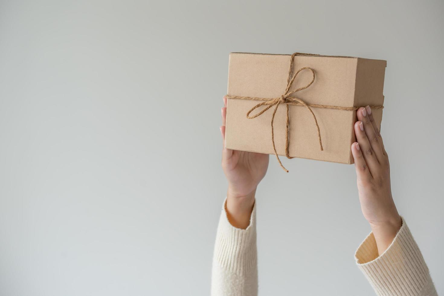 donna mani Tenere presente scatola con un' nastro arco. minimalista concetto di dando un' regalo. foto