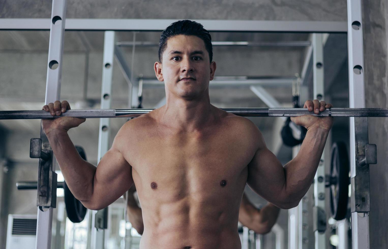 muscolare uomo allenarsi con sollevamento manubrio a sollevamento pesi stazione nel fitness. foto