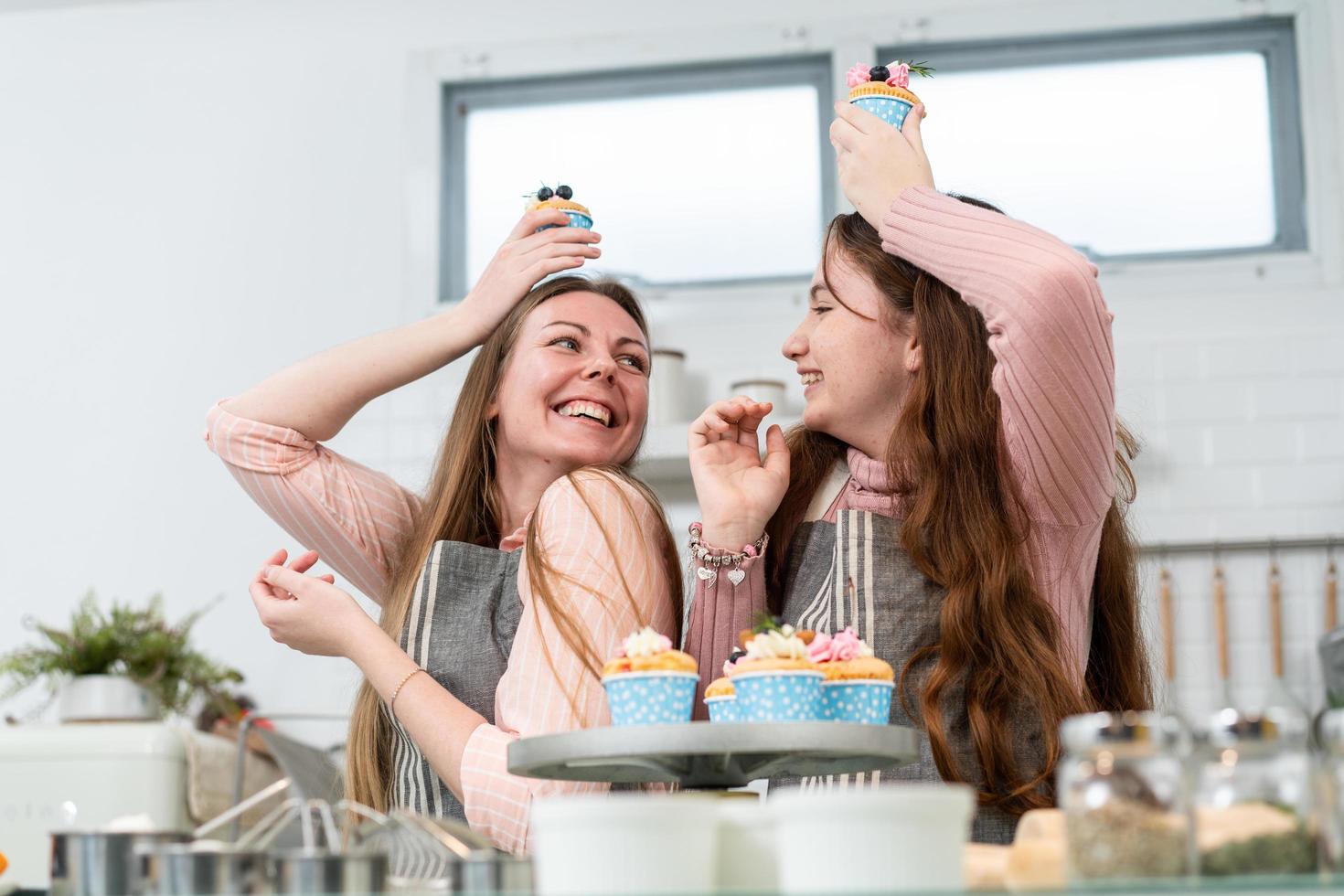 giocoso madre e figlia ridere e Sorridi mostrando torta foto