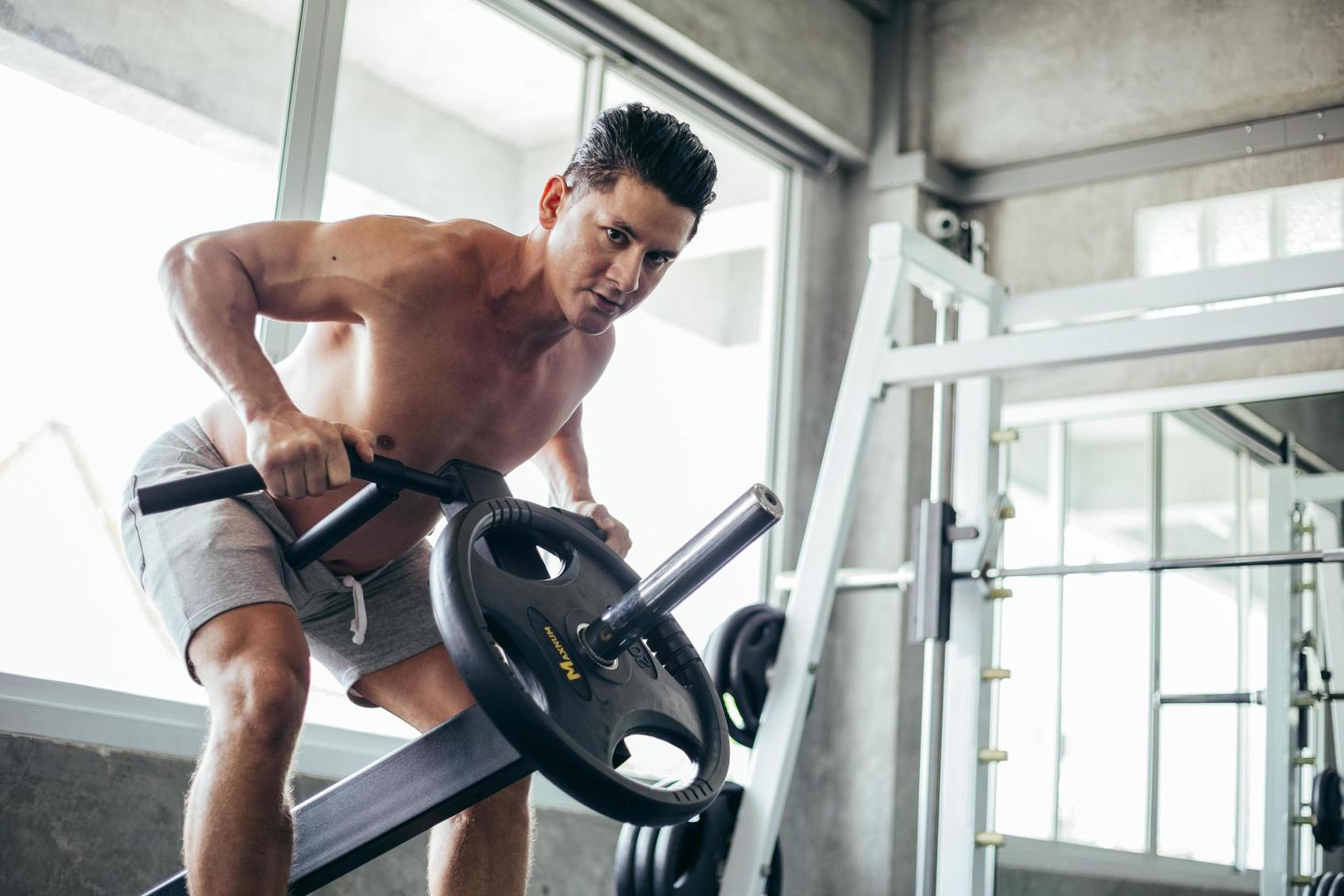 muscolare uomo allenarsi con sollevamento manubrio nel fitness foto