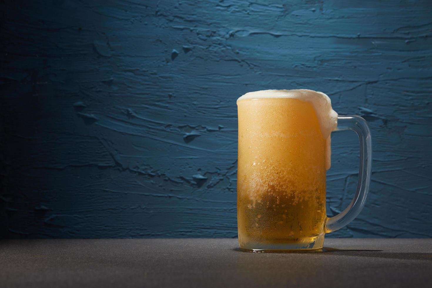 birra in una tazza su sfondo blu foto