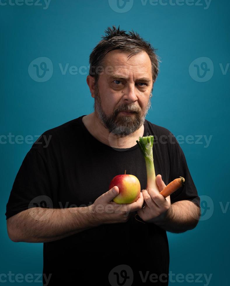 uomo nel un' nero maglietta detiene frutta e verdure foto