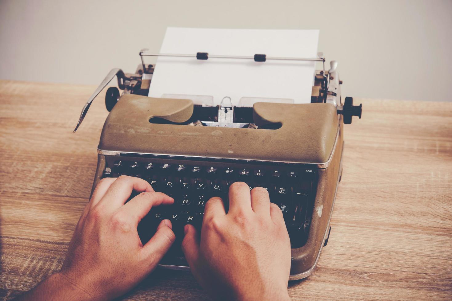 mani che digitano sulla macchina da scrivere vintage sul tavolo di legno foto