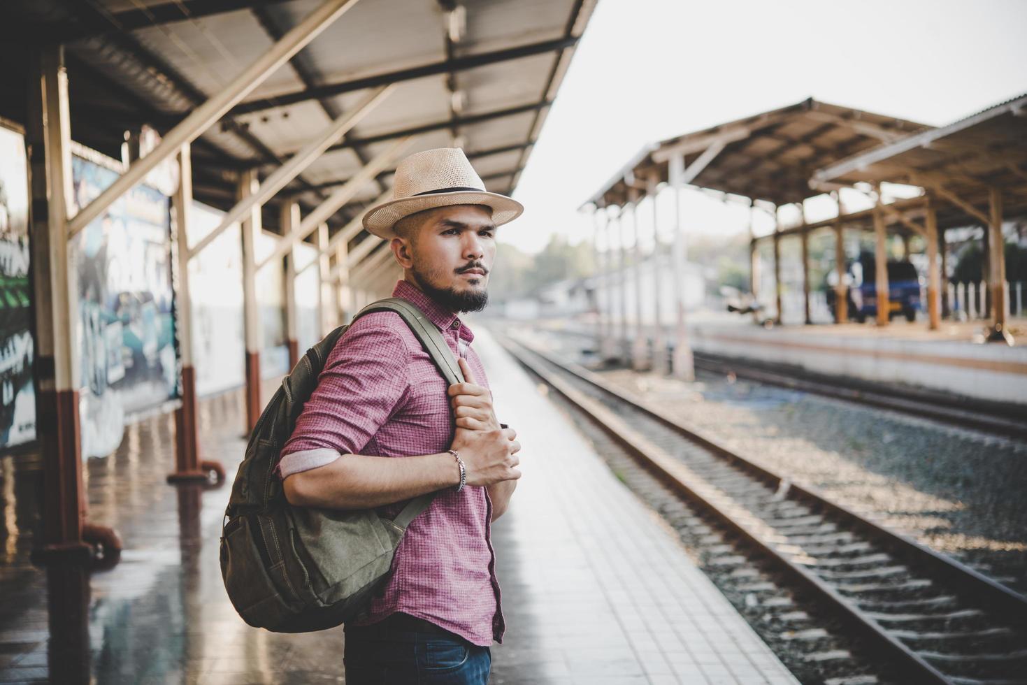 uomo giovane hipster che cammina attraverso la stazione ferroviaria foto