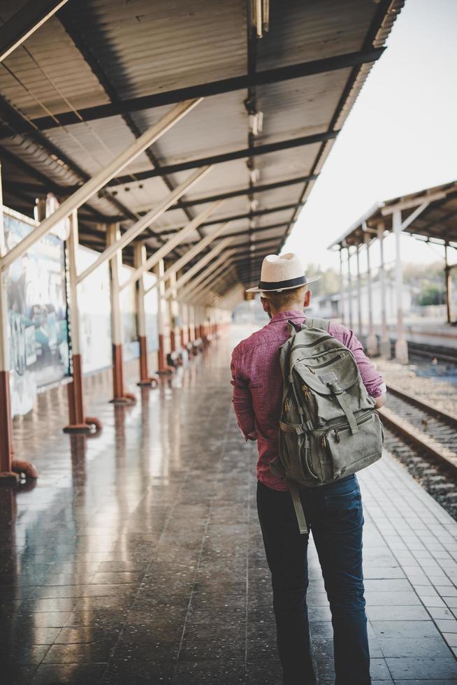 uomo giovane hipster che cammina attraverso la stazione ferroviaria foto