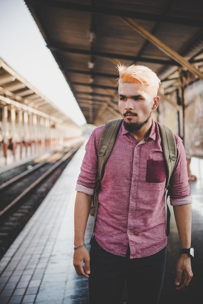 uomo giovane hipster che cammina attraverso la stazione ferroviaria foto