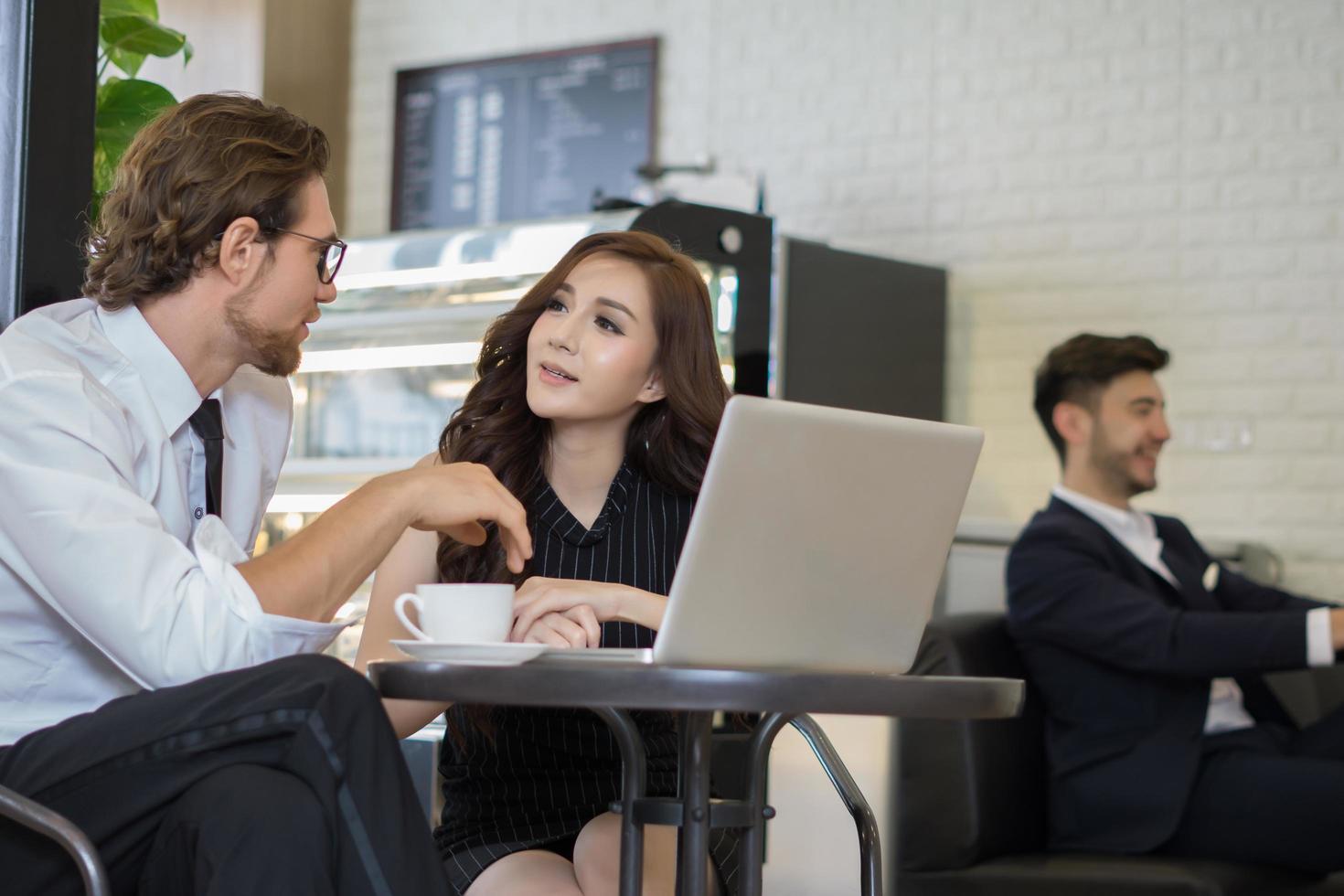 colleghi felici che si incontrano insieme al caffè che lavora al computer portatile foto