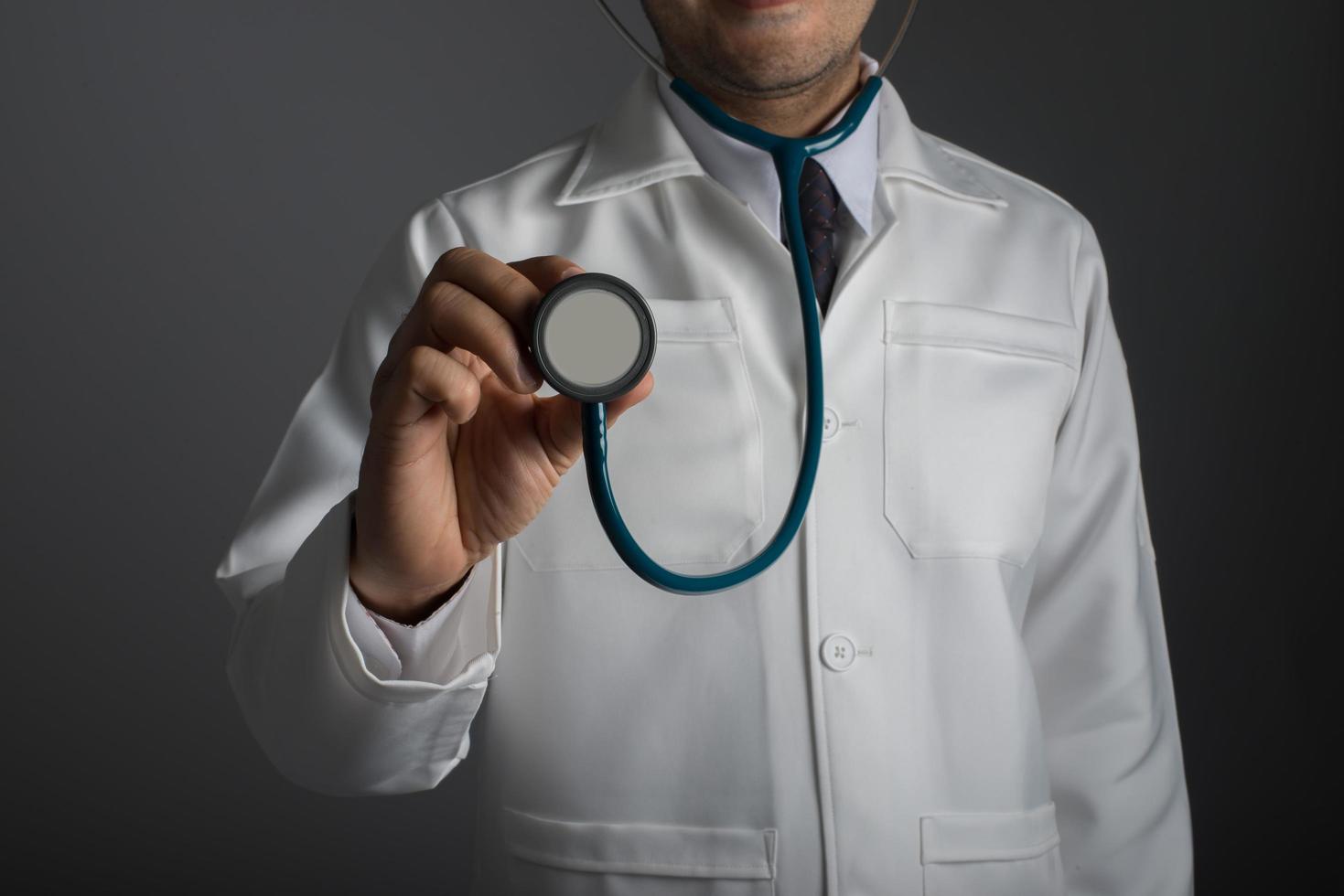 medico con uno stetoscopio isolato su sfondo grigio foto