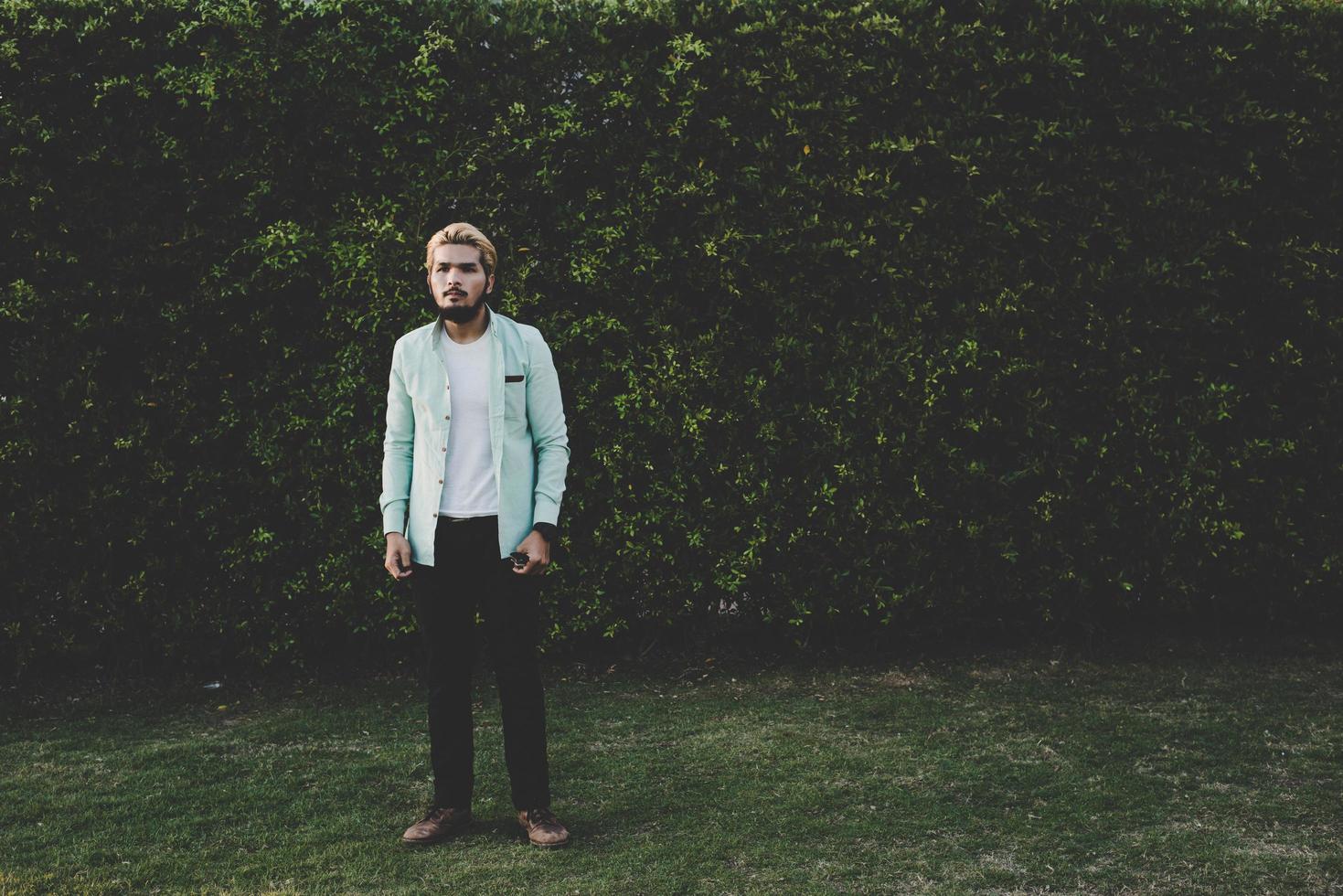 bel giovane hipster uomo che guarda lontano mentre in piedi all'aperto foto