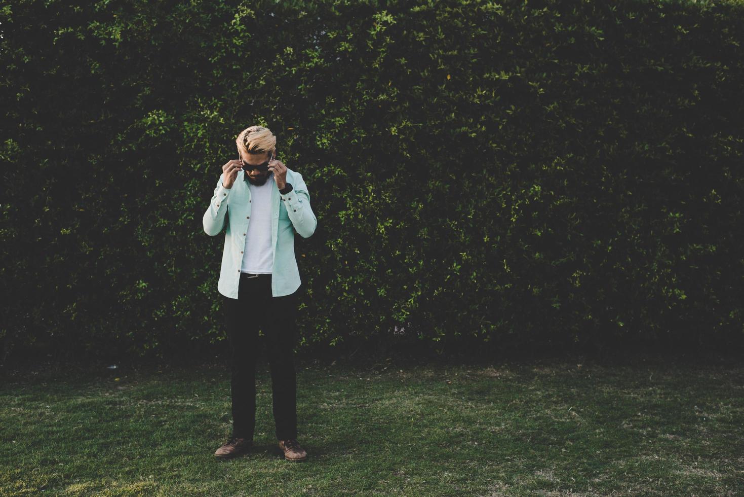 bel giovane hipster uomo che guarda lontano mentre in piedi all'aperto foto