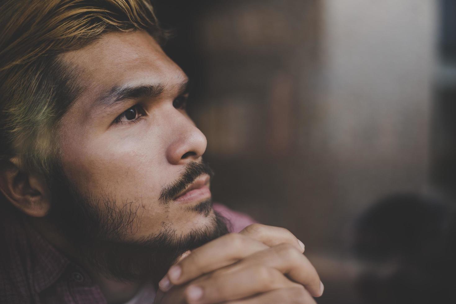 pensieroso giovane hipster uomo seduto in una caffetteria pensando foto