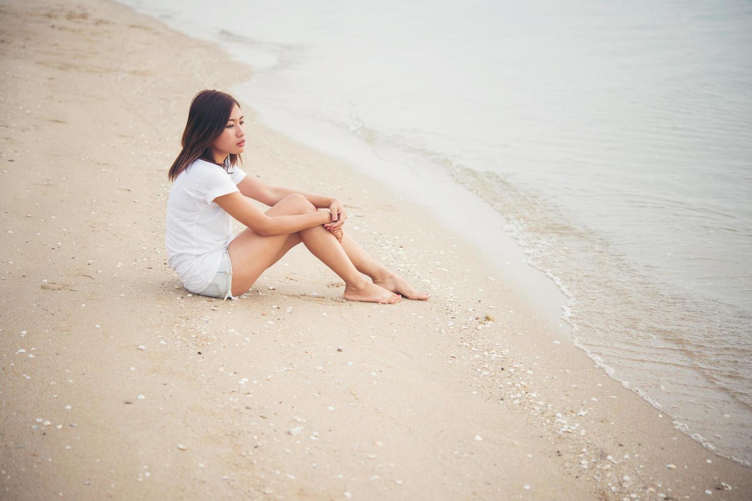 giovane donna seduta sulla spiaggia foto