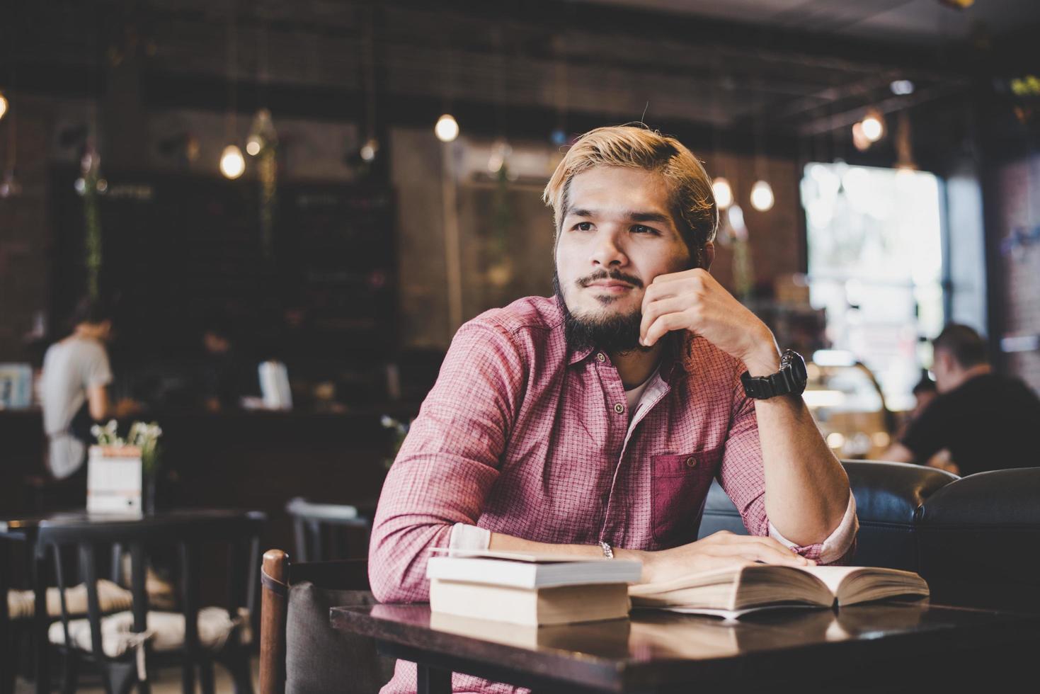 giovane barbuto hipster leggendo un libro in un caffè foto