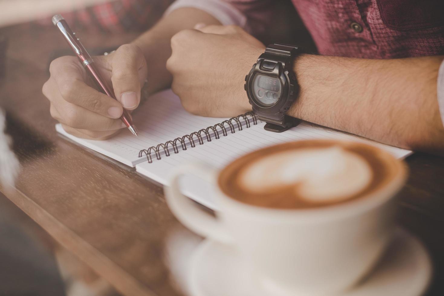 una tazza di caffè sulla barra di legno accanto a un hipster in un bar foto