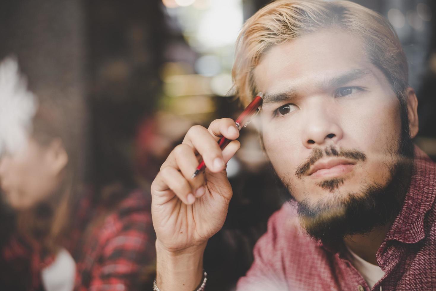 pensieroso giovane hipster uomo seduto in una caffetteria pensando foto