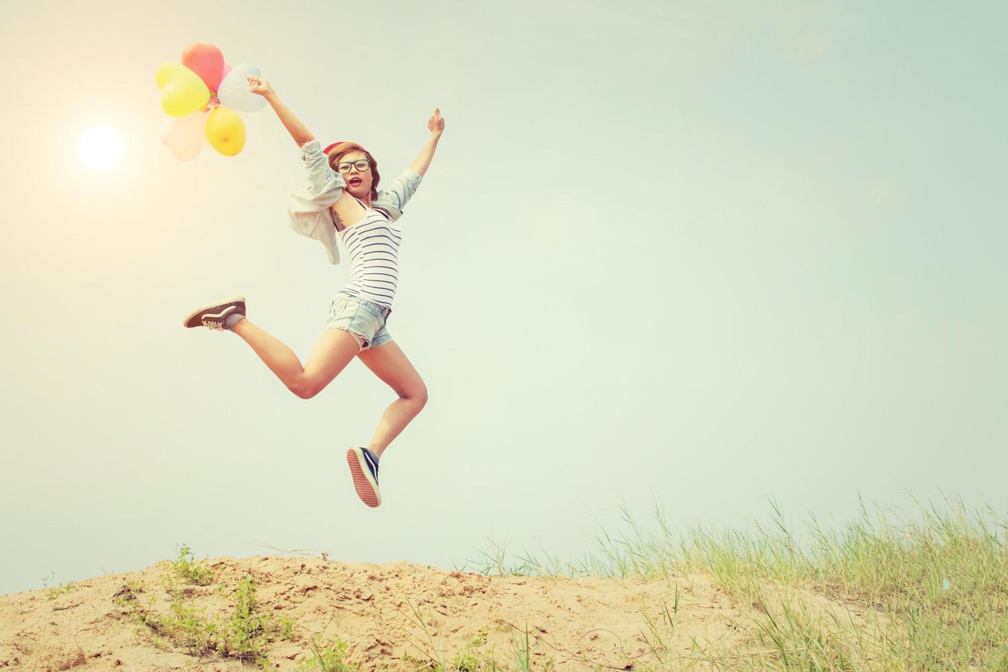 bella ragazza che salta con palloncini sulla spiaggia foto