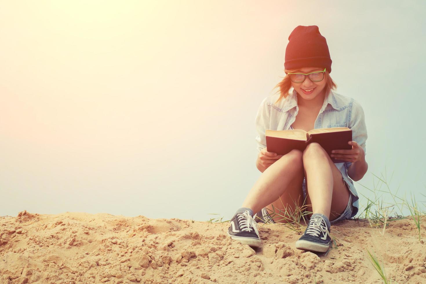 bella giovane donna che legge un libro in spiaggia foto