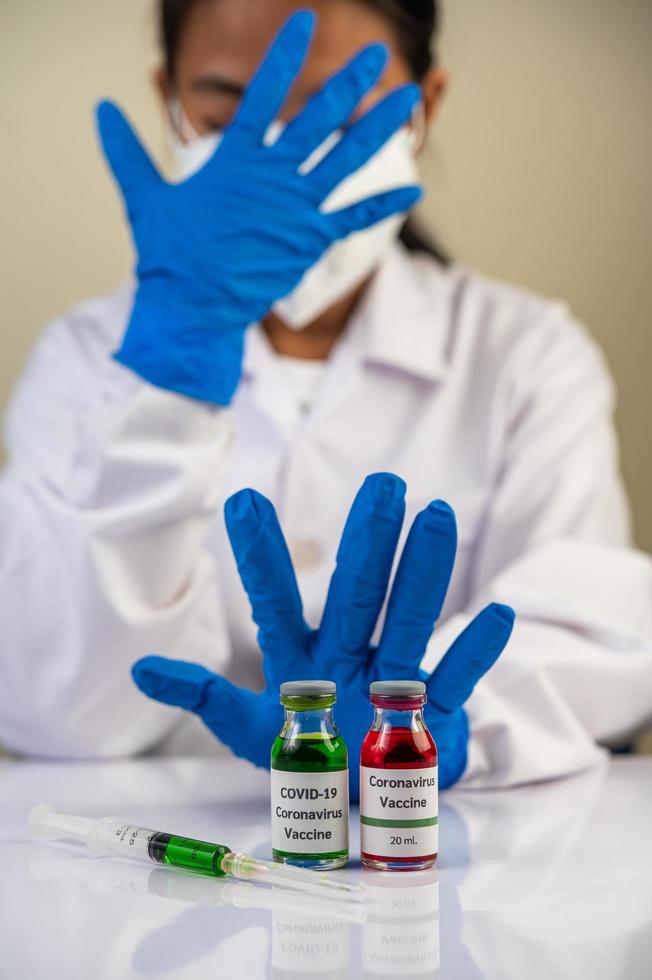 scienziato che indossa un guanto blu fa le mani a un vaccino inaccettabile foto
