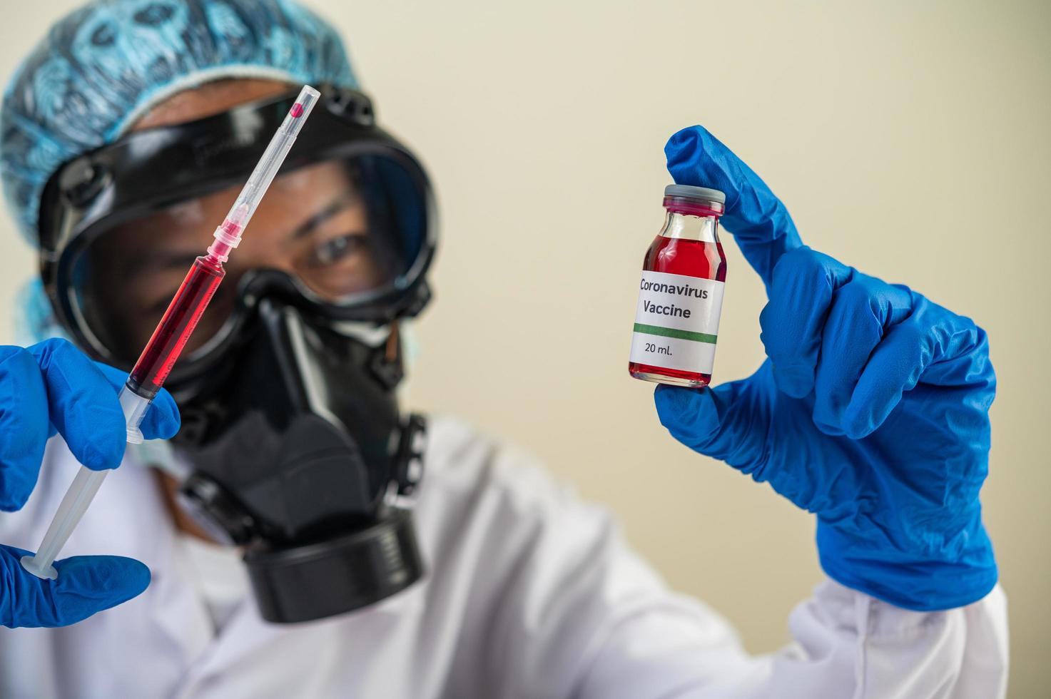 scienziato che indossa maschere protettive e guanti che tengono una siringa con un vaccino per prevenire il covid-19 foto