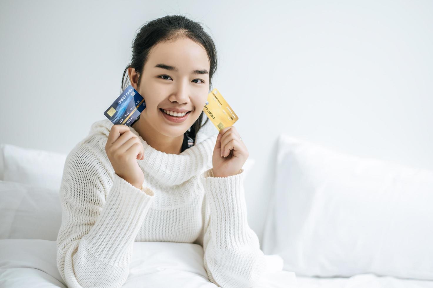 giovane donna con una carta di credito sorridente sul letto foto