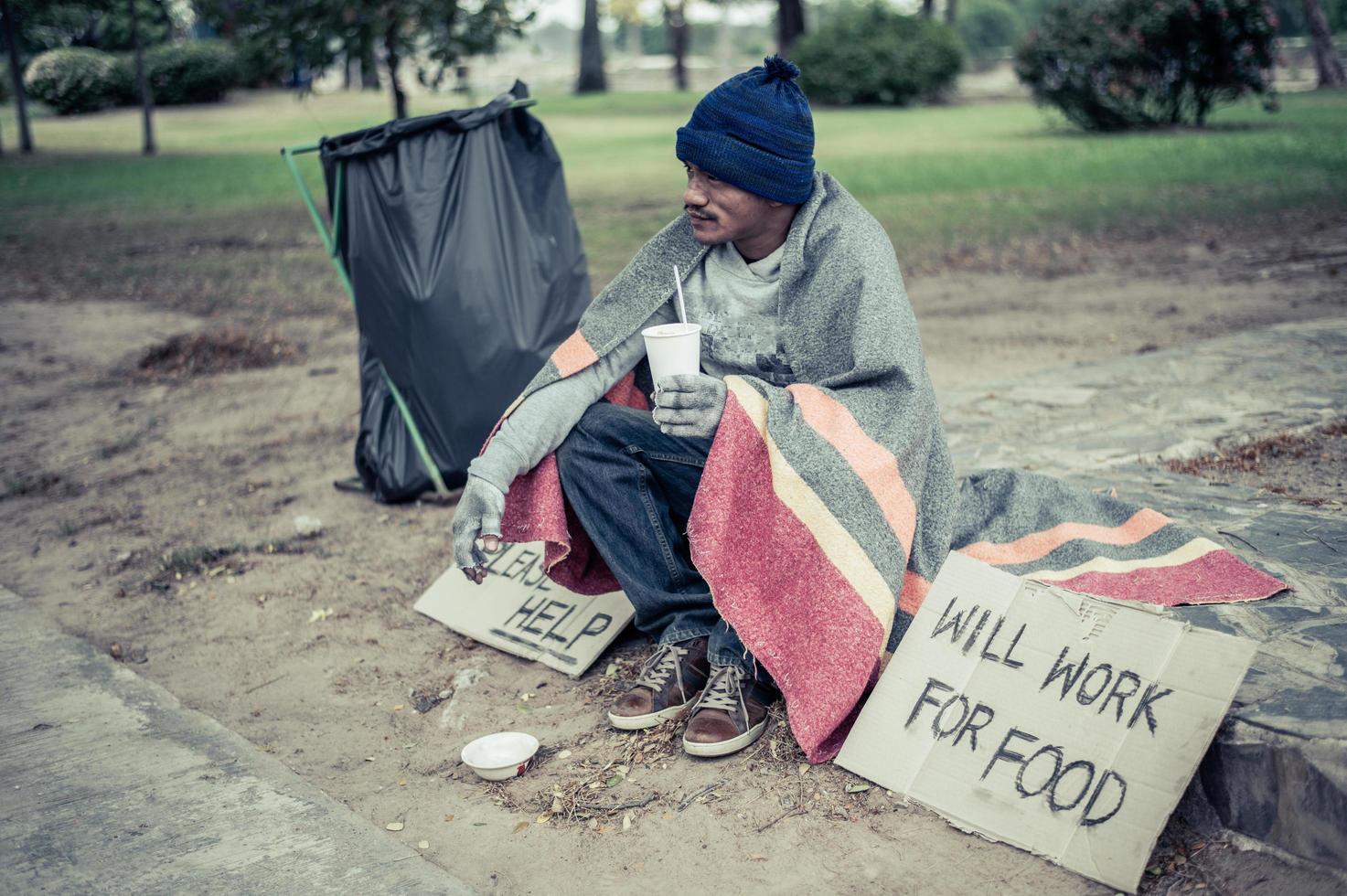 senzatetto avvolto in un panno e mangiare spaghetti foto