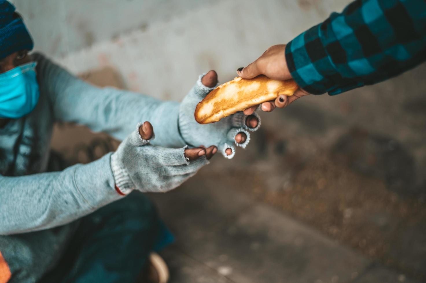 la macchina per il pane dà a un mendicante sul ciglio della strada foto