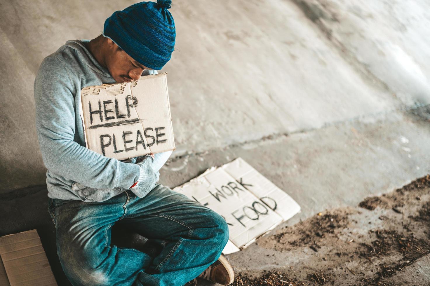 mendicanti seduti sotto il ponte con un segno foto