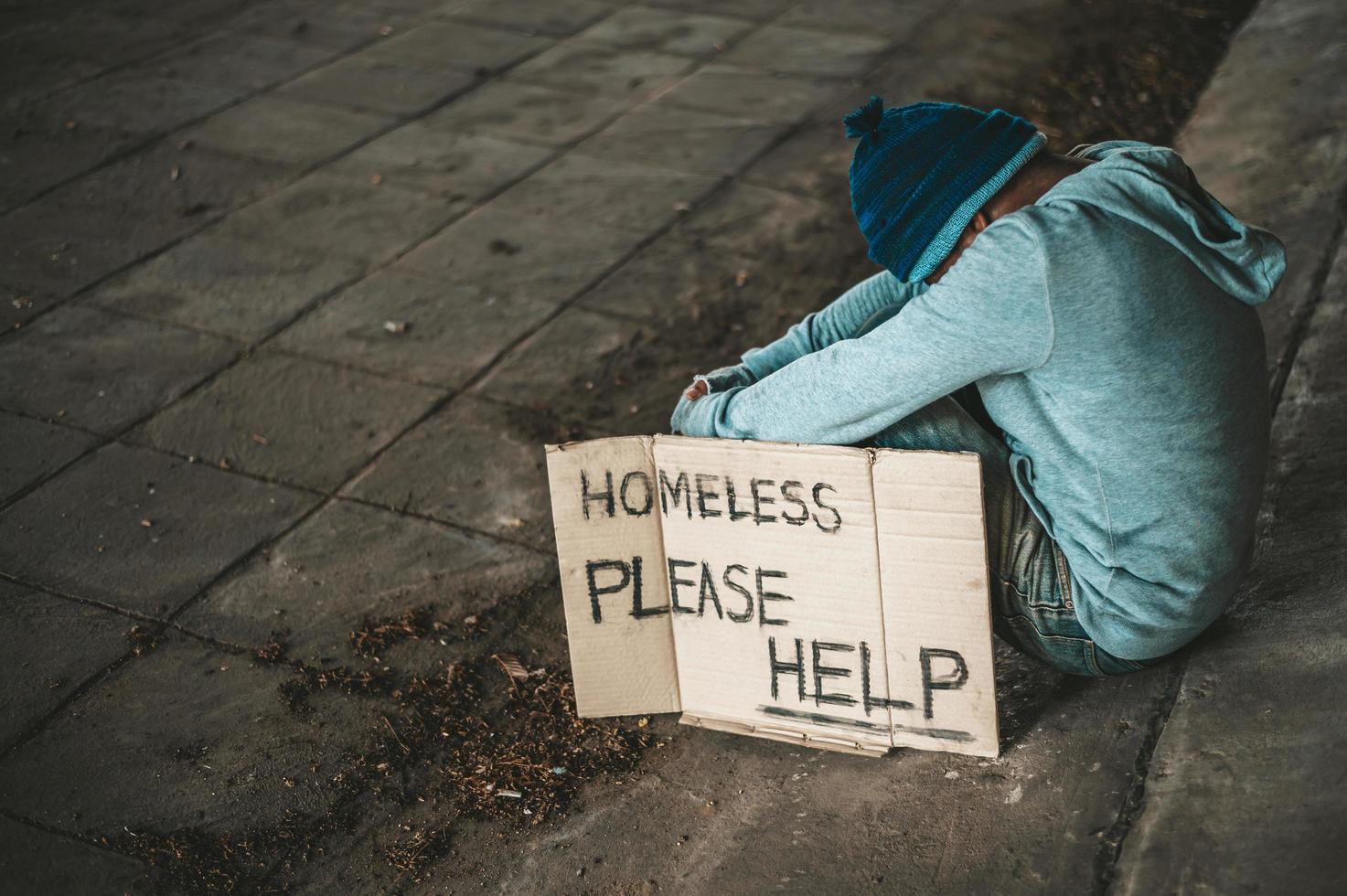 mendicante siede sotto il ponte con un messaggio di senzatetto foto