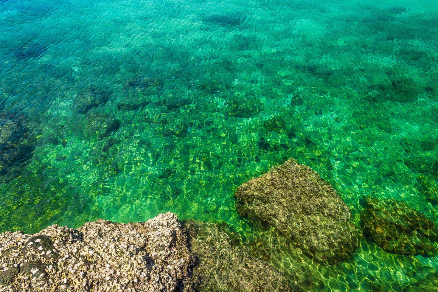 roccia dell'isola tropicale sulla spiaggia con acqua verde blu chiaro foto