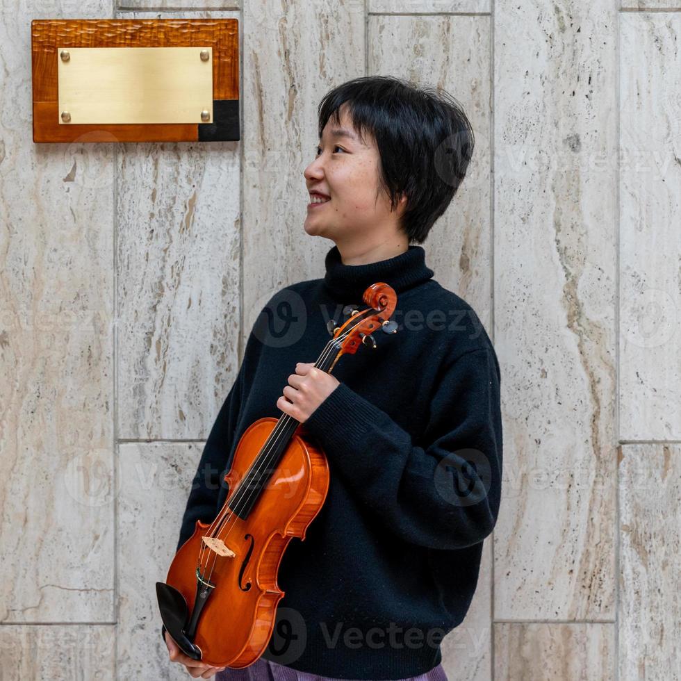 giovane Cinese femmina violino creatore mostrando sua appena fatto violino all'aperto foto