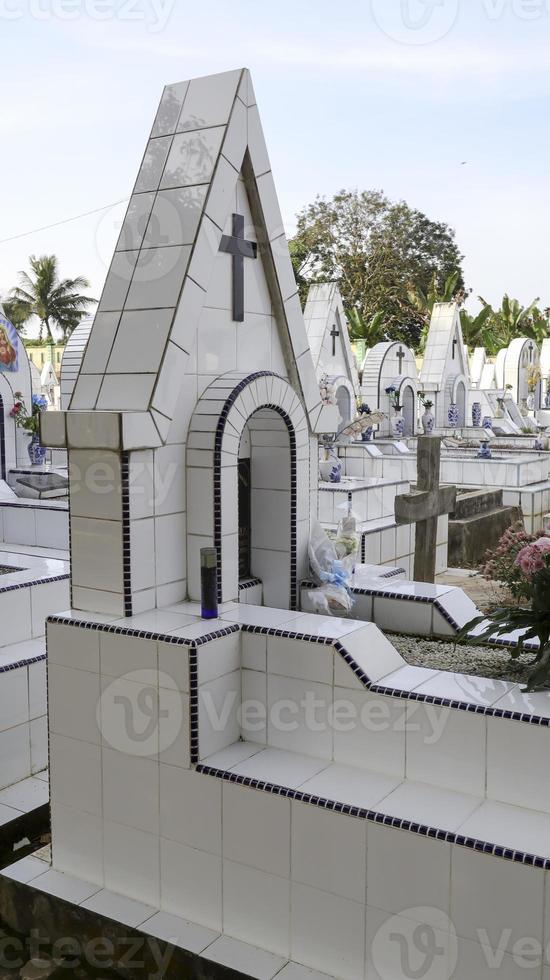 il pubblico cimitero contiene identico bianca ceramica tombe con fiori. foto