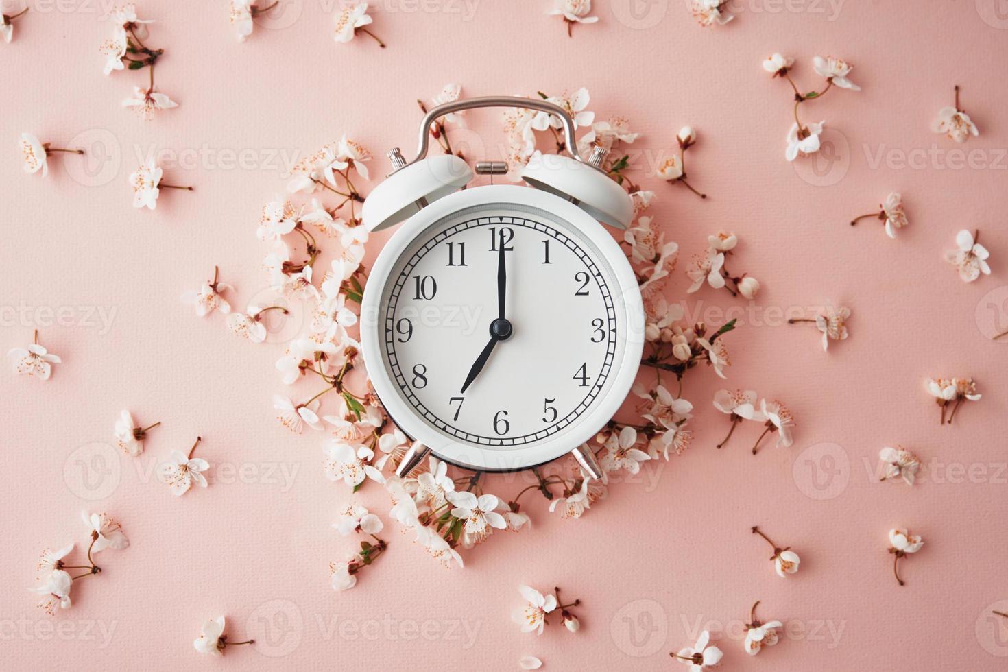 allarme orologio su rosa sfondo con fiori. modificare tempo concetto foto