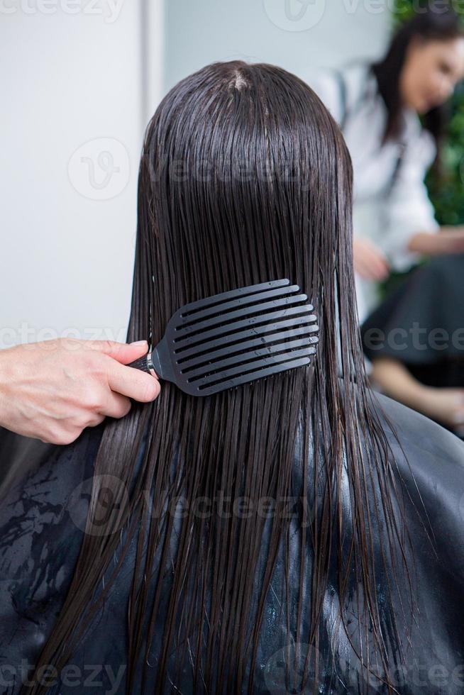 parrucchiere si applica un' capelli maschera per dritto nero capelli. capelli cura a il bellezza salone. foto