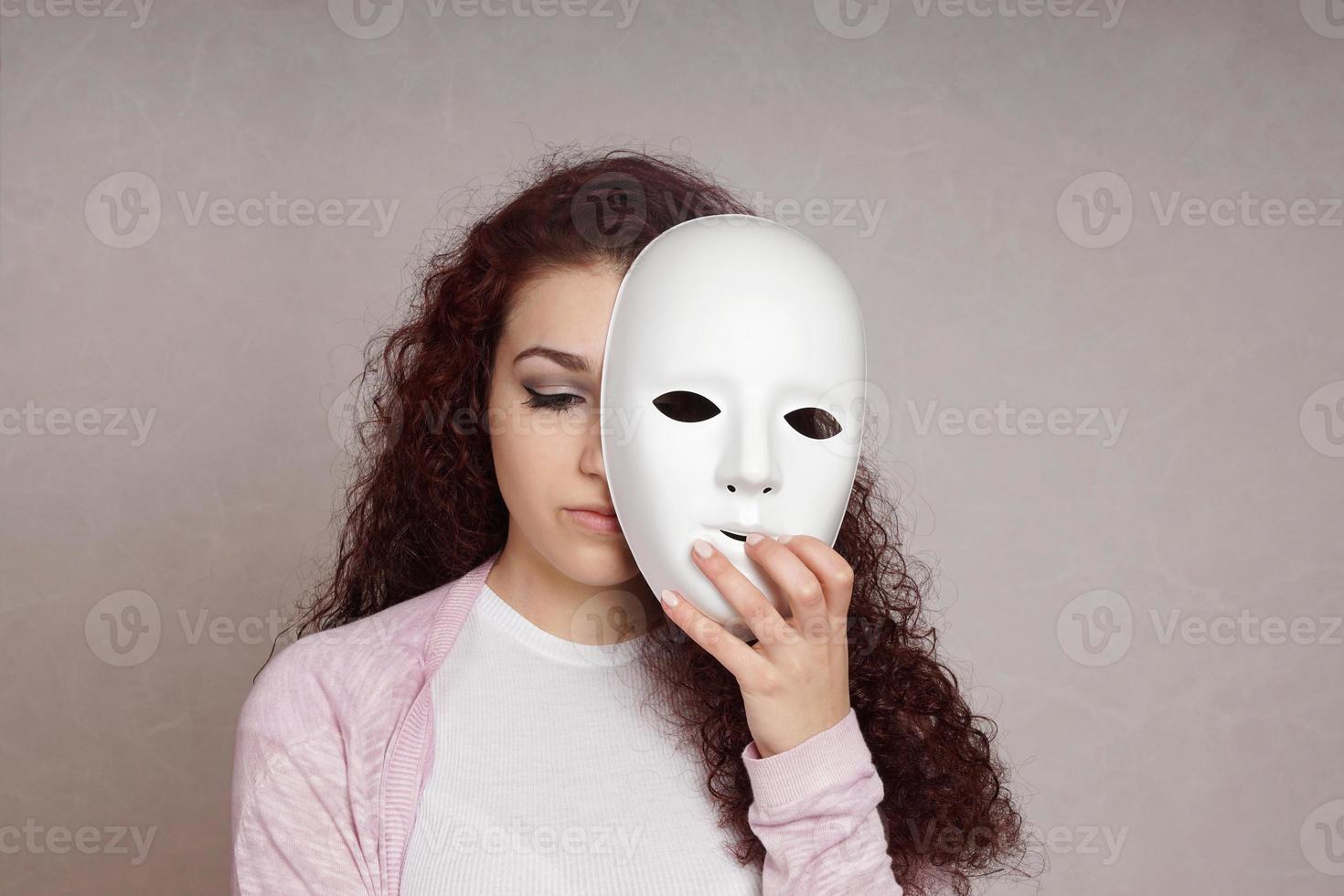triste ragazza nascondiglio viso dietro a maschera foto