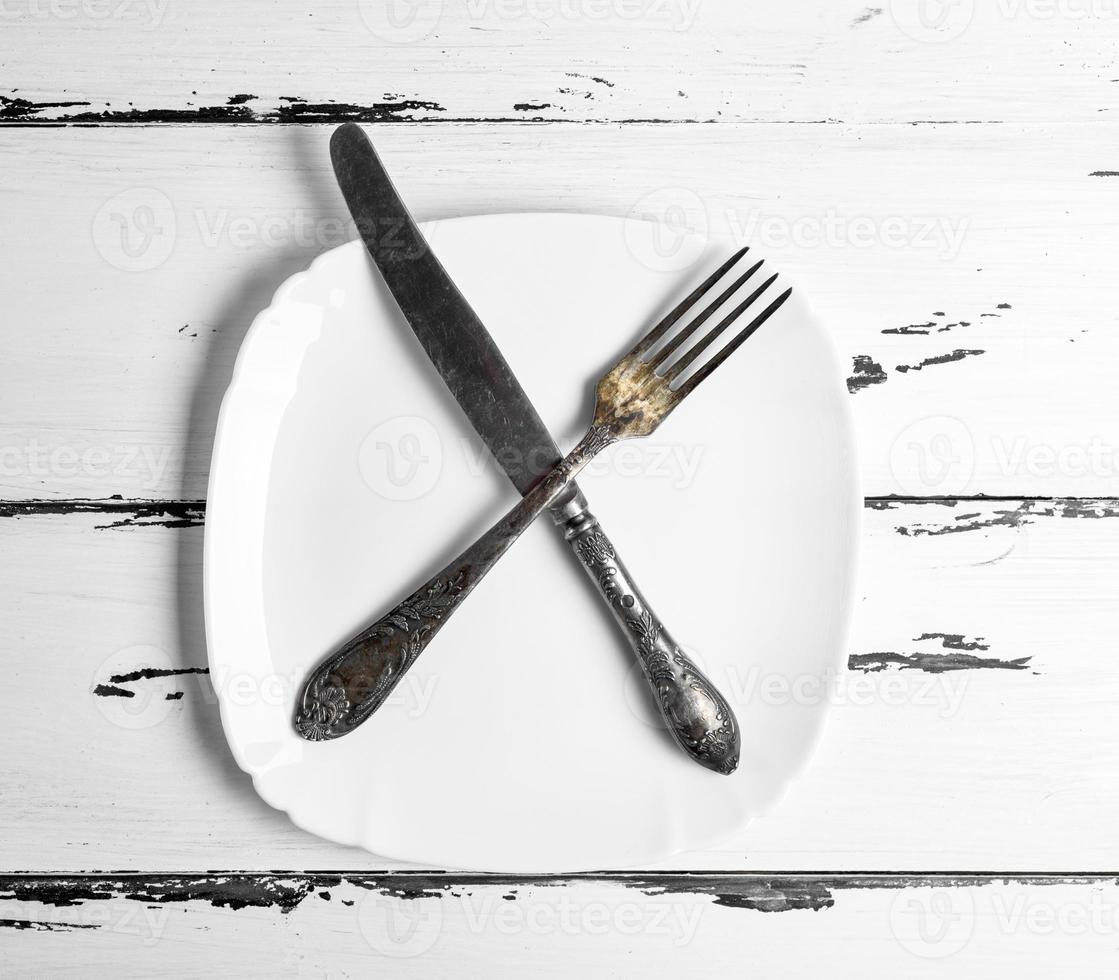 ferro Vintage ▾ forchetta con coltello dire bugie su un' vuoto bianca piazza piatto foto