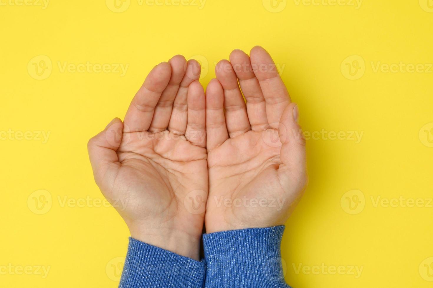 Due femmina mani piegato palma per palma su un' giallo sfondo foto
