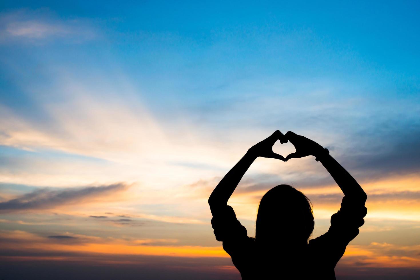 sagoma delle mani di una donna a forma di cuore con alba foto