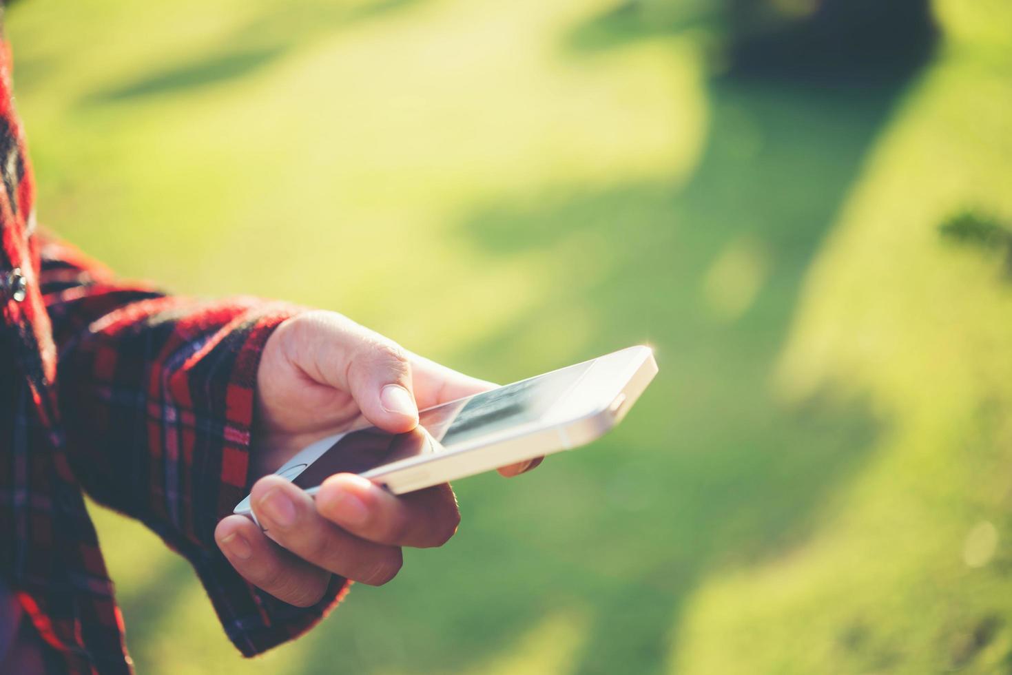 giovane donna che utilizza uno smartphone all'aperto in un parco foto