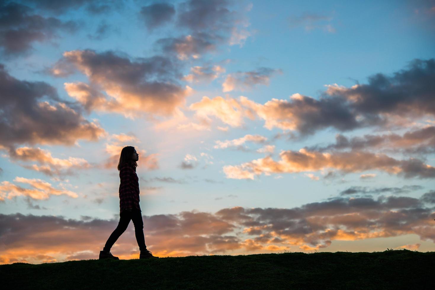 silhouette di una donna che cammina al tramonto foto