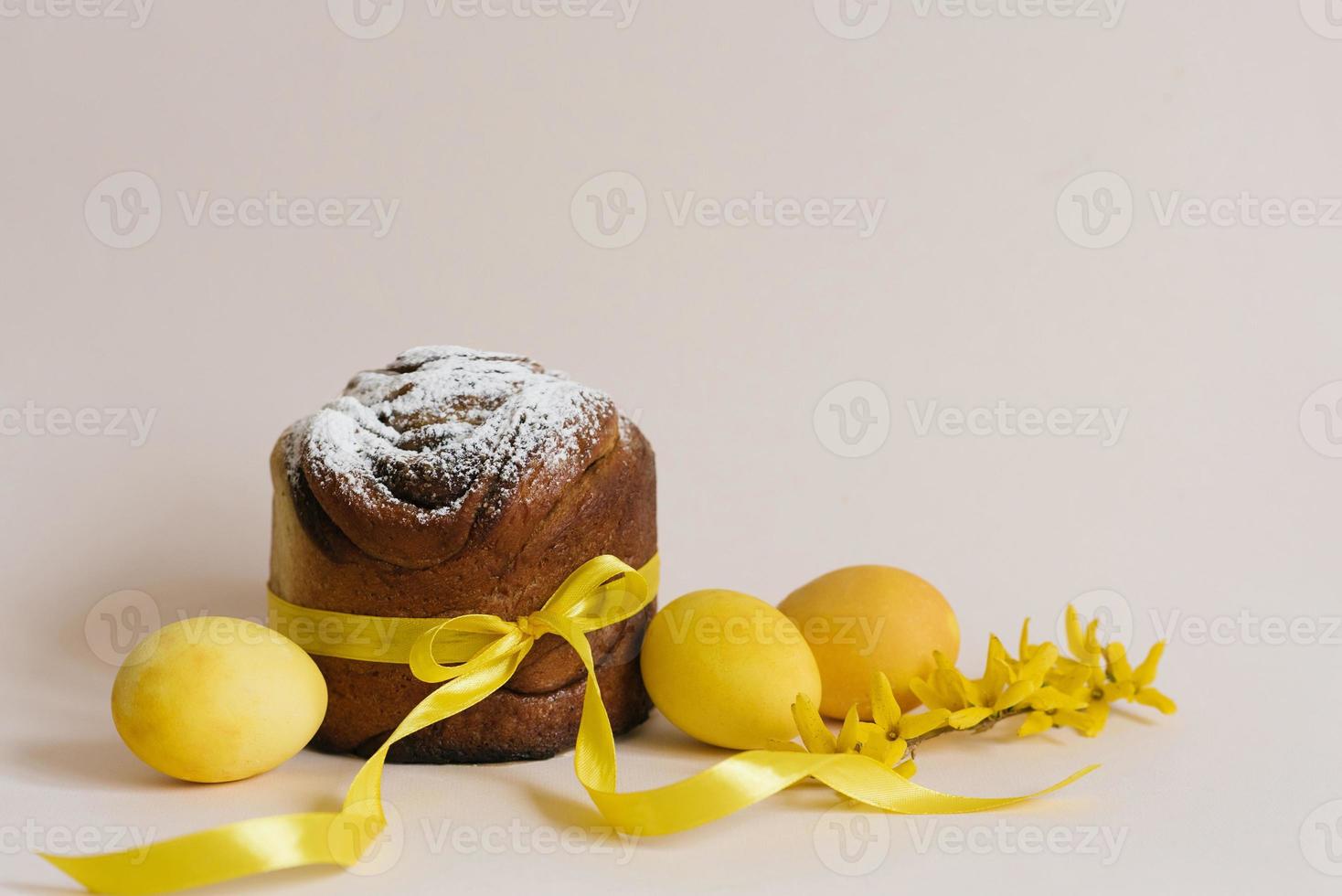 impostato di tradizionale russo e ucraino Pasqua torte kulich paska pane cosparso con in polvere zucchero totale, con giallo fiori, dipinto uova, al di sopra di il tavolo. foto