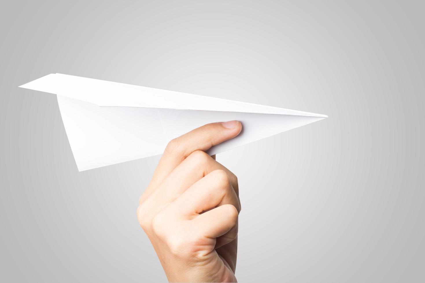 mano della donna che tiene un aeroplano di carta isolato su priorità bassa bianca foto