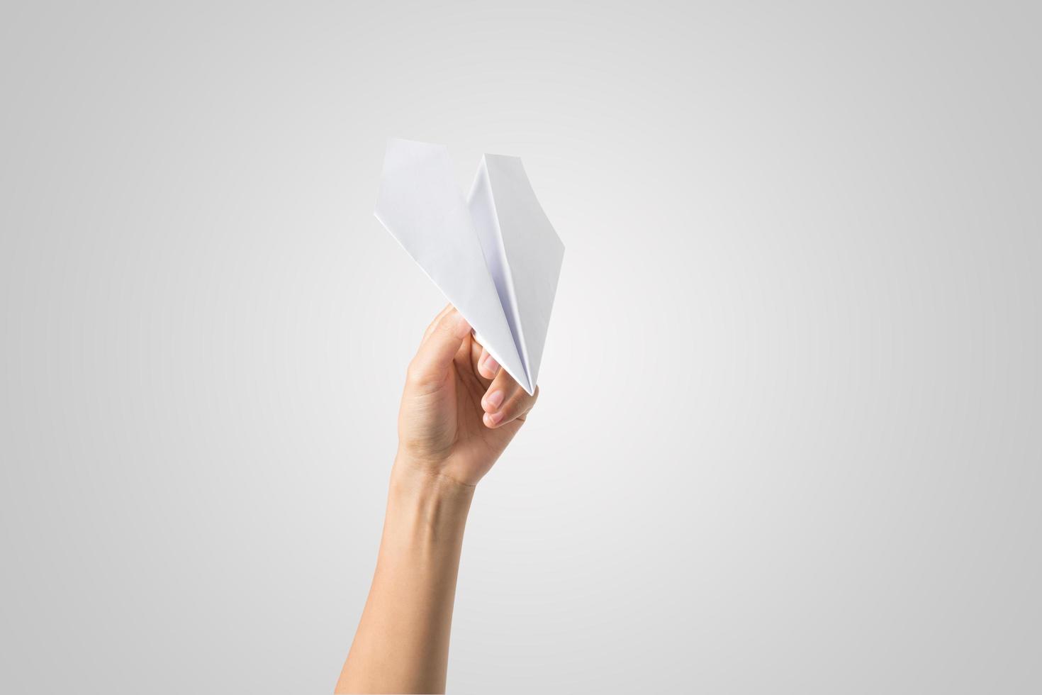 mano della donna che tiene un aeroplano di carta isolato su priorità bassa bianca foto