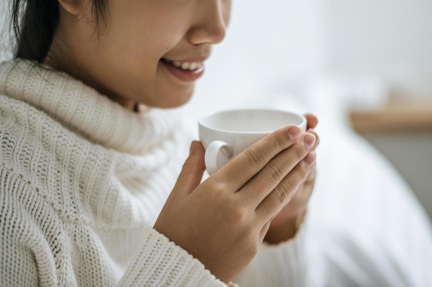 giovane donna con una tazza di caffè a letto foto