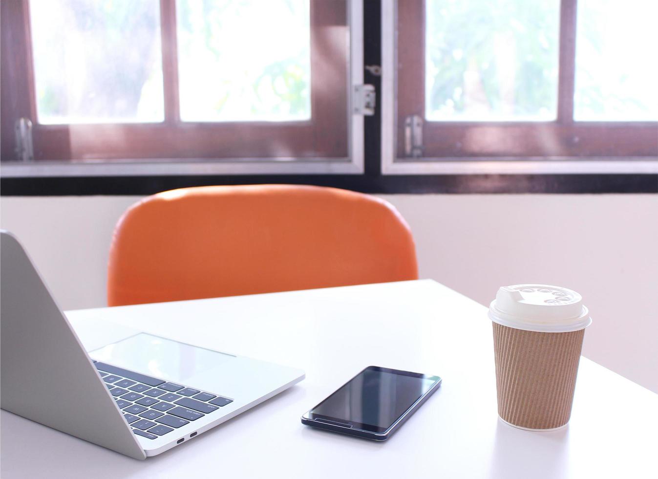 scrivania con un laptop, un telefono e un caffè foto