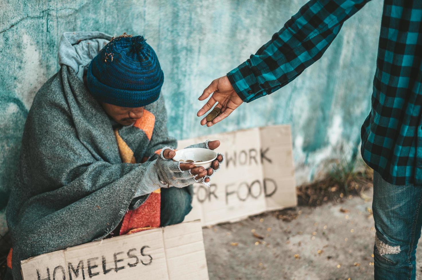 il panettiere dà a un mendicante sul ciglio della strada foto